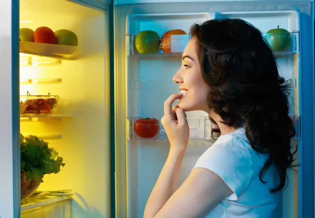 Das Mädchen schaut während des schnellen Gewichtsverlusts in den Kühlschrank